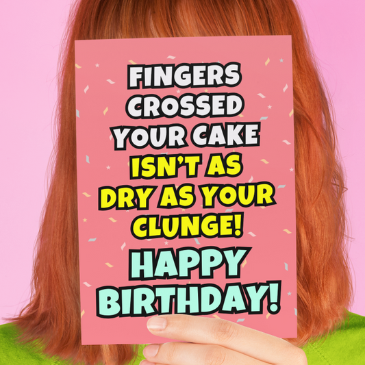 Person wearing a green shirt holding a pink card with a humorous birthday message against a pink background