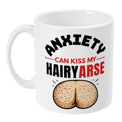 A white ceramic mug with a humorous graphic that reads 'ANXIETY CAN KISS MY HAIRYARSE' in black and red text, above an illustration of a hairy rear end, on a plain white background.