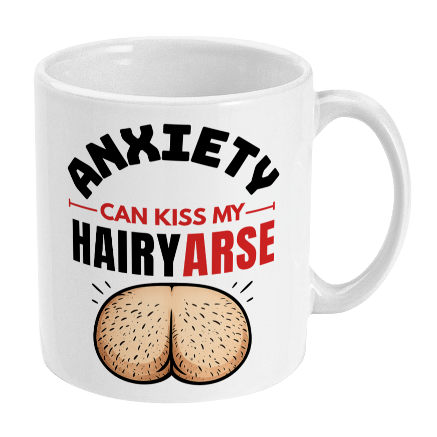 A white ceramic coffee mug featuring a humorous graphic with the text 'ANXIETY CAN KISS MY HAIRYARSE' in black and red lettering, accompanied by an illustration of two hairy butts. The mug is shown on a clean white background.