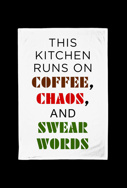 White Tea towel with text 'This kitchen runs on coffee, chaos, and swear words' on a black background