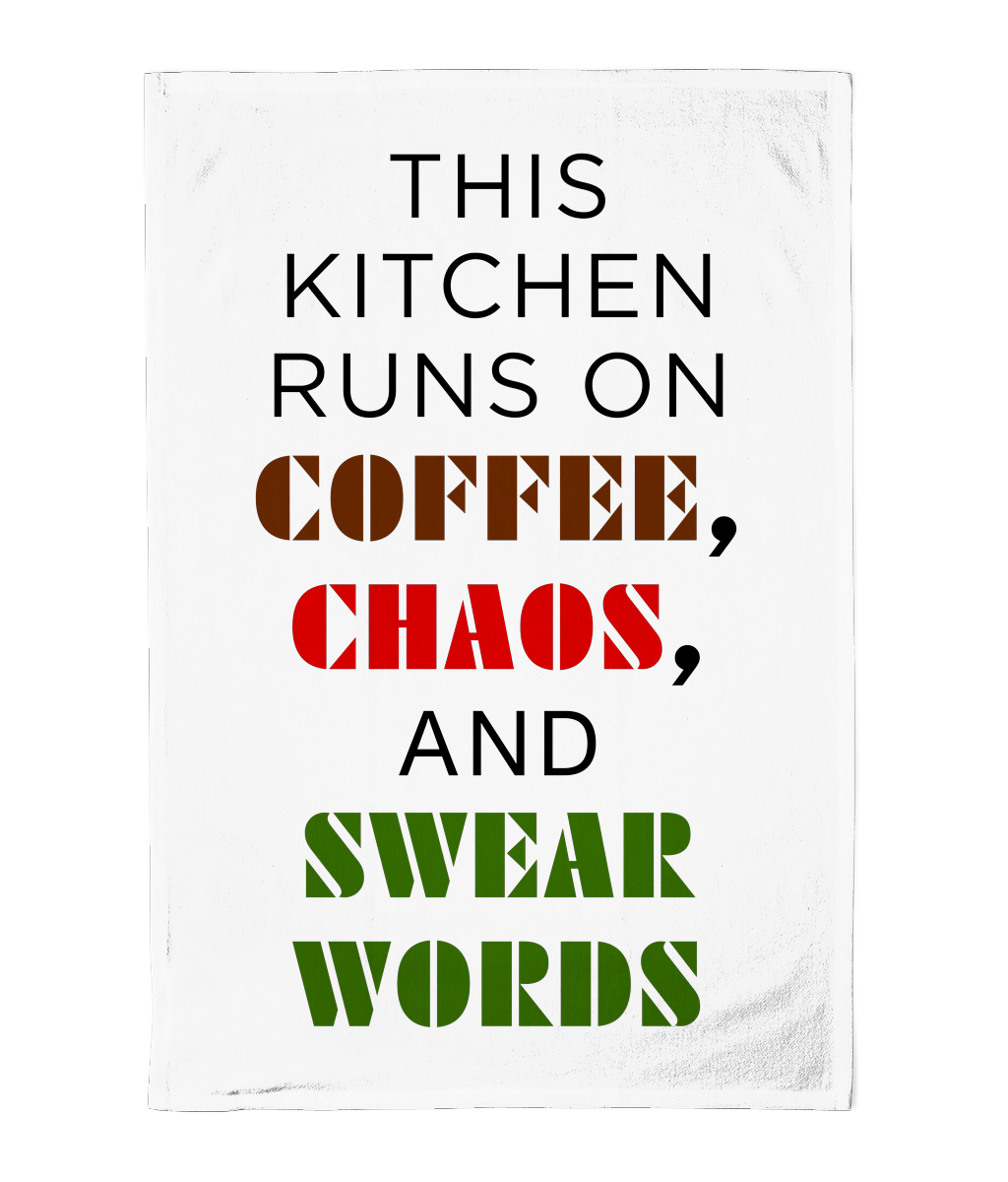 Tea towel with text 'This kitchen runs on coffee, chaos, and swear words' in black, red, and green on a white background.