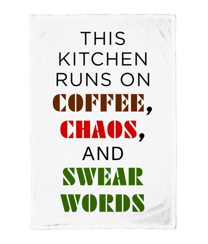 Tea towel with text 'This kitchen runs on coffee, chaos, and swear words' in black, red, and green on a white background.