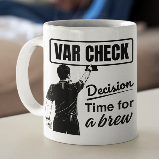 Mug with text and graphic on a table in a room with a blurred person sitting on a couch.