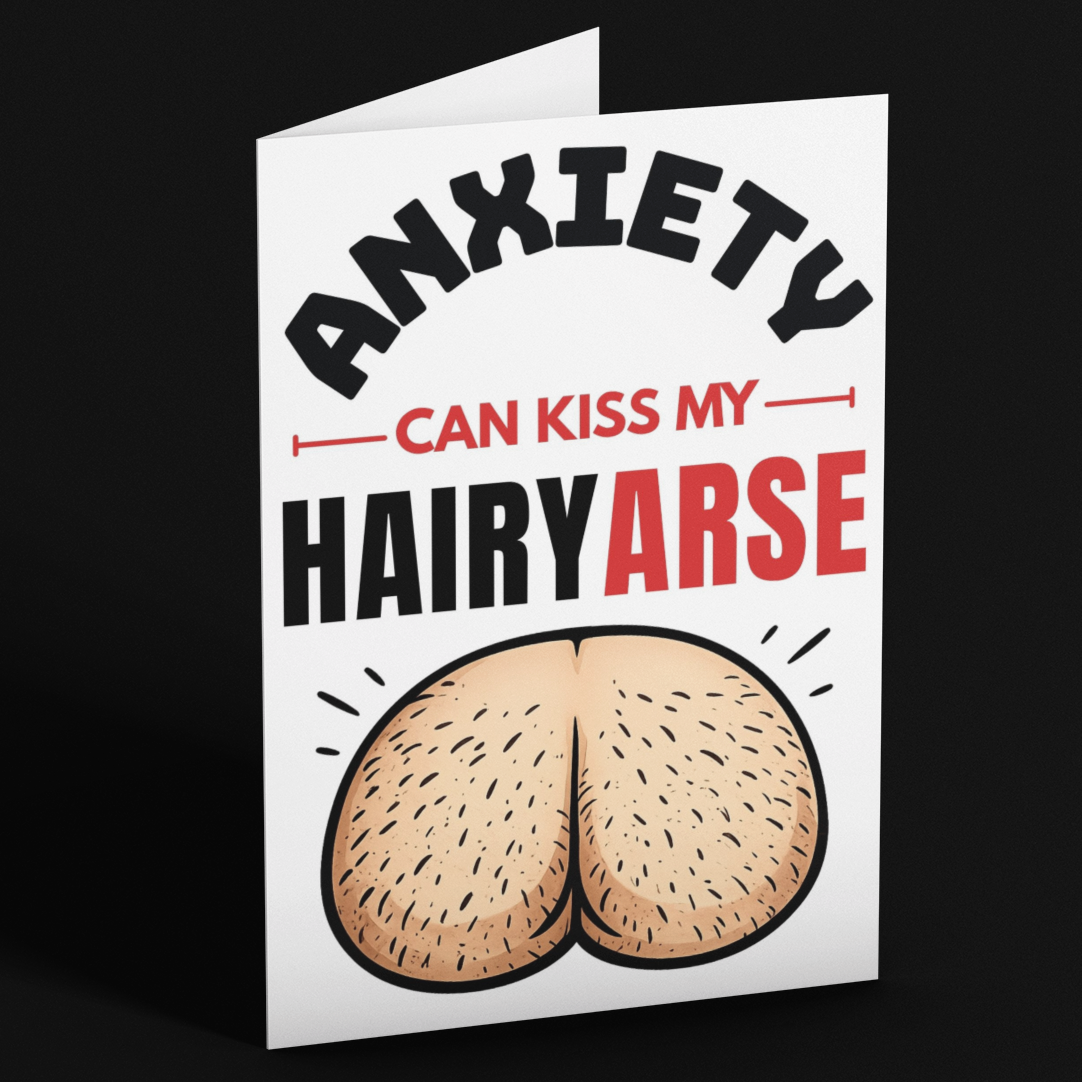 A folded white greeting card standing upright on a black background. The card features the text 'ANXIETY CAN KISS MY HAIRYARSE' in black and red lettering, with a cartoon illustration of a hairy rear at the bottom.