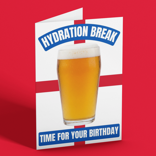 A folded greeting card standing upright on a red background. The card has a white base with a red cross motif, blue banners reading 'HYDRATION BREAK' at the top and 'TIME FOR YOUR BIRTHDAY' at the bottom, and a large photo of a pint of beer in the center.