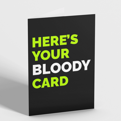 A black greeting card standing upright on a light gray background, with bold text reading 'HERE'S YOUR BLOODY CARD' in lime green and white.