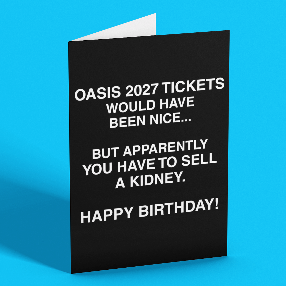 A black greeting card standing upright on a bright blue background. The card has white text that reads, 'OASIS 2027 TICKETS WOULD HAVE BEEN NICE.