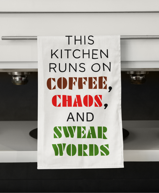 Kitchen towel with humorous text hanging on a kitchen cabinet.