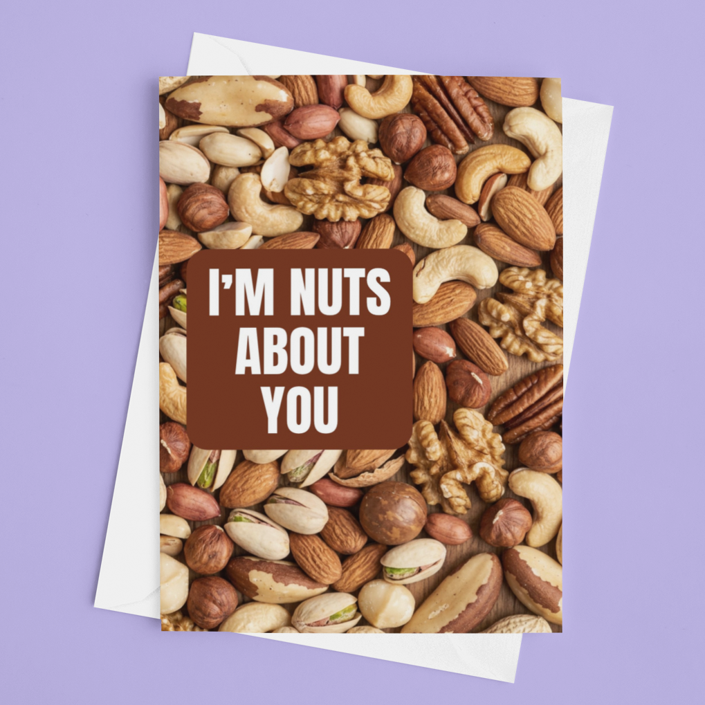 A greeting card featuring a close-up photo of assorted nuts and a brown label with the text 'I'M NUTS ABOUT YOU', shown on top of a white card against a solid lavender background.