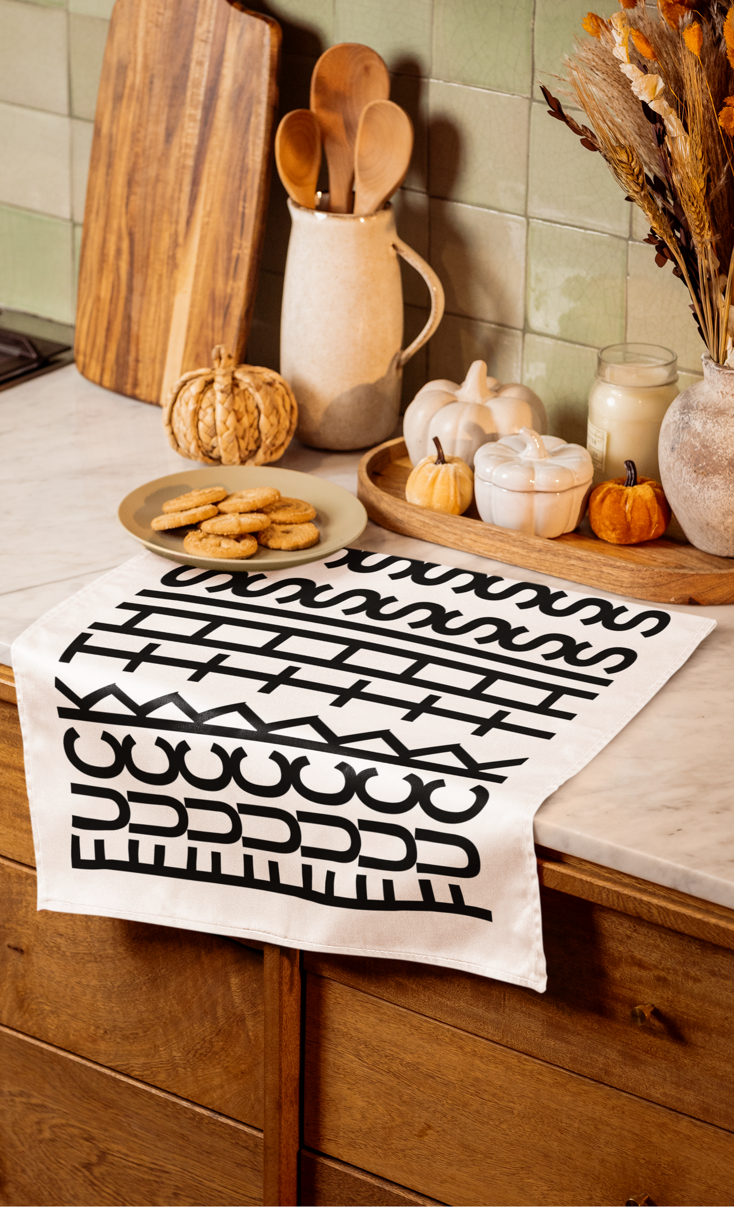 Kitchen counter with a patterned towel, cookies, and decorative items on a wooden shelf.