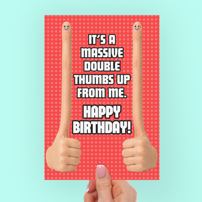 Hand holding a birthday card with double thumbs-up design on a light blue background