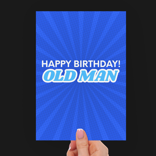 A hand holding a blue birthday card with the text 'HAPPY BIRTHDAY! OLD MAN' in white and light blue, set against a solid black background.