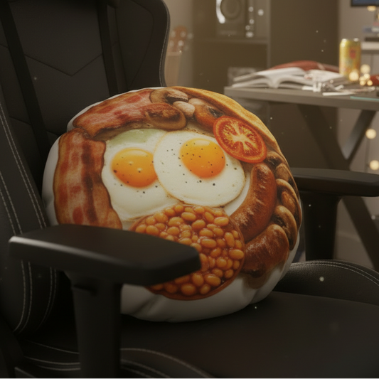 A round novelty pillow printed with a breakfast theme, resting on the armrest of a black gaming chair in a home office setup.