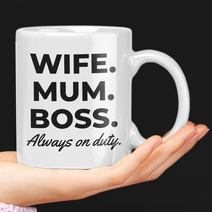 White mug with text 'Wife. Mum. Boss. Always on duty.' held by a hand against a black background